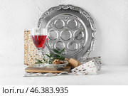 Passover Seder plate with glass of wine, walnuts and matza on white background. Стоковое фото, фотограф Pixel_shot / Фотобанк Лори