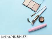Makeup brushes, mascara, highlighter and eyebrows gel on blue background. Стоковое фото, фотограф Pixel_shot / Фотобанк Лори