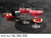 Board with glasses of Cosmopolitan cocktail and pomegranate on black background. Стоковое фото, фотограф Pixel_shot / Фотобанк Лори