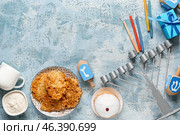 Hannukah composition with menorah, candles, potato pancakes and donut on light blue table. Стоковое фото, фотограф Pixel_shot / Фотобанк Лори