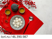 Red mat with bowl of tangyuan, tea and Chinese decor on white grunge background. Dongzhi Festival. Стоковое фото, фотограф Pixel_shot / Фотобанк Лори