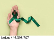 Female hand holding green ribbon on color background. National cerebral palsy awareness month. Стоковое фото, фотограф Pixel_shot / Фотобанк Лори