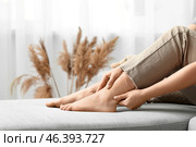 Young woman suffering from joint pain on sofa in living room. Стоковое фото, фотограф Pixel_shot / Фотобанк Лори