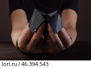 Hands of male fortune teller with paper cootie catcher on dark background. Стоковое фото, фотограф Pixel_shot / Фотобанк Лори