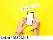 Woman with mobile phone and in handcuffs on color background. Concept of addiction to gadget. Стоковое фото, фотограф Pixel_shot / Фотобанк Лори