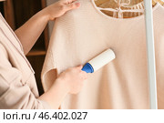 Woman cleaning clothes with lint roller, closeup. Стоковое фото, фотограф Pixel_shot / Фотобанк Лори