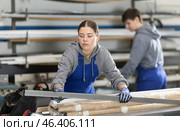 Girl glazer employee in blue overall works in glass processing shop. Стоковое фото, фотограф Яков Филимонов / Фотобанк Лори