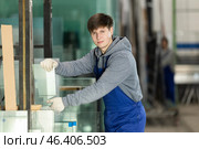 Guy glazer employee in blue overall works in glass processing shop. Стоковое фото, фотограф Яков Филимонов / Фотобанк Лори