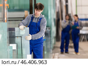 Guy glazer employee in blue overall works in glass processing shop. Стоковое фото, фотограф Яков Филимонов / Фотобанк Лори