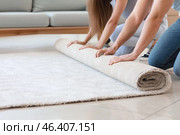 Young couple unrolling carpet on floor. Стоковое фото, фотограф Pixel_shot / Фотобанк Лори