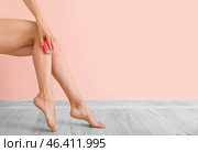 Beautiful young woman epilating legs near color wall. Стоковое фото, фотограф Pixel_shot / Фотобанк Лори