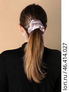 Woman with ponytail and silk scrunchy on beige background, back view. Стоковое фото, фотограф Pixel_shot / Фотобанк Лори