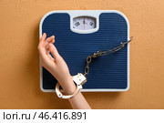 Female hand, scales and handcuffs on color background. Anorexia concept. Стоковое фото, фотограф Pixel_shot / Фотобанк Лори