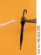 Hands of Caucasian woman and African-American man with umbrella on color background. Racism concept. Стоковое фото, фотограф Pixel_shot / Фотобанк Лори