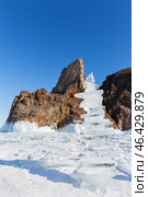 Winter landscape of frozen Baikal Lake in February sunny day. High ice pyramid made of transparent ice floes against backdrop of famous Cape Khoboy - natural landmark of Olkhon Island. Winter travels. Стоковое фото, фотограф Виктория Катьянова / Фотобанк Лори