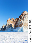 Baikal Lake on sunny February day. View of famous Cape Sagan-Khushun or Three Brothers Cliff - natural landmark of Olkhon Island and tourist destination against background of blue sky on sunny day. Стоковое фото, фотограф Виктория Катьянова / Фотобанк Лори
