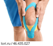 Спортивный человек с физиотерапевтической лентой, нанесенной на колено на белом фоне, близком расстоянии. Стоковое фото, фотограф Pixel_shot / Фотобанк Лори