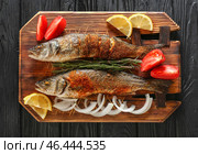 Доска с вкусно приготовленной рыбой сибаса на темном столе. Стоковое фото, фотограф Pixel_shot / Фотобанк Лори