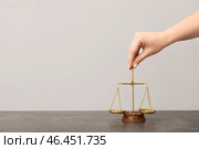 Женская рука кладет весы правосудия на стол. Стоковое фото, фотограф Pixel_shot / Фотобанк Лори