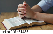 Person is praying with their hands on a book. Стоковое AI-видео, аниматор Sergey Grishin / Фотобанк Лори