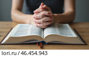 Woman is praying with her hands on her lap while looking at a Bible. Стоковое AI-видео, аниматор Sergey Grishin / Фотобанк Лори