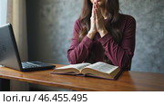 Woman is praying in front of a laptop and a book. Стоковое AI-видео, аниматор Sergey Grishin / Фотобанк Лори