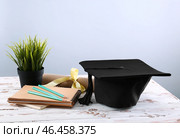 Минометная доска, диплом и канцелярские товары на столе. Концепция окончания средней школы. Стоковое фото, фотограф Pixel_shot / Фотобанк Лори