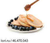Лить мед на тарелку с вкусными блинами и ягодами на белом фоне. Стоковое фото, фотограф Pixel_shot / Фотобанк Лори