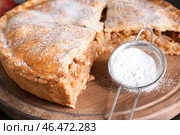 Вкусный яблочный пирог и сито с сахарной пудрой на деревянной доске, крупным планом. Стоковое фото, фотограф Pixel_shot / Фотобанк Лори