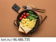 Деревянная доска со сковородкой с вкусной яичницей, помидорами, зеленью и хлебом на цветном фоне. Стоковое фото, фотограф Pixel_shot / Фотобанк Лори