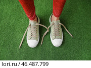 Женщина в кроссовках с развязанными ботинками на зеленом фоне. Стоковое фото, фотограф Pixel_shot / Фотобанк Лори