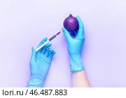 Женщина в медицинских перчатках вводит вакцину в новогодний бал на цветном фоне. Стоковое фото, фотограф Pixel_shot / Фотобанк Лори