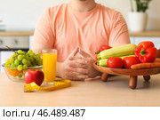 Молодой толстяк со здоровой пищей, стаканом сока и измерительной лентой за столом на кухне, крупным планом. Стоковое фото, фотограф Pixel_shot / Фотобанк Лори