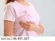 Молодая женщина с розовой лентой на светлом фоне, крупным планом. Концепция осведомленности о раке молочной железы. Стоковое фото, фотограф Pixel_shot / Фотобанк Лори