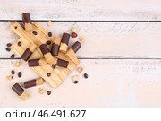 Разделочная доска с кучей вкусных вафельных трубочек, кофейных зерен и орехов на светлом деревянном фоне. Стоковое фото, фотограф Pixel_shot / Фотобанк Лори