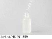 Капание натуральной сыворотки из пипетки во флакон на светлом фоне. Стоковое фото, фотограф Pixel_shot / Фотобанк Лори