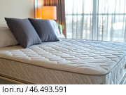Comfortable mattress with pillows in bedroom interior design showing hotel room or apartment suite. Стоковое AI-изображение, AI-художник Юрий Поздников / Фотобанк Лори