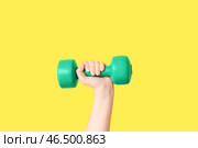 Женская рука с зеленым гантелем на желтом фоне, крупным планом. Стоковое фото, фотограф Pixel_shot / Фотобанк Лори