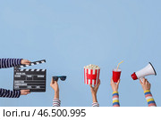 Множество рук с киношным хлопушкой, ведром попкорна и мегафоном на голубом фоне. Стоковое фото, фотограф Pixel_shot / Фотобанк Лори