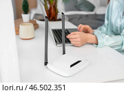 Современный wi-fi роутер на столе у женщины, использующей ноутбук в спальне, крупным планом. Стоковое фото, фотограф Pixel_shot / Фотобанк Лори