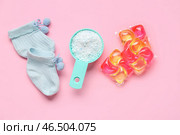 Совок с порошком для стирки, гелевой капсулой и детскими носками на розовом фоне. Стоковое фото, фотограф Pixel_shot / Фотобанк Лори