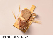 Деревянная доска с нарезанным батоном хлеба, колосьями пшеницы и зернами на сером фоне. Стоковое фото, фотограф Pixel_shot / Фотобанк Лори