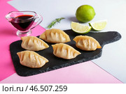 Грифельная тарелка с вкусной японской гёдзой и соусом на цветном фоне. Стоковое фото, фотограф Pixel_shot / Фотобанк Лори