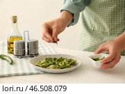 Шеф-повар посыпать вкусные равиоли на тарелку с травами. Стоковое фото, фотограф Pixel_shot / Фотобанк Лори