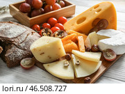 Ассортимент вкусных сыров с хлебом на деревянном столе. Стоковое фото, фотограф Pixel_shot / Фотобанк Лори