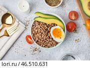Тарелка вкусной гречневой каши с яйцом всмятку и свежими овощами на сером столе. Стоковое фото, фотограф Pixel_shot / Фотобанк Лори