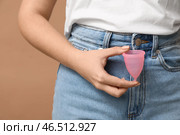 Прекрасная молодая женщина с менструальной чашей на коричневом фоне, крупным планом. Стоковое фото, фотограф Pixel_shot / Фотобанк Лори