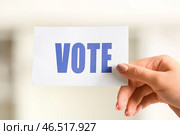 Женщина держит бумагу с текстом VOTE на избирательном участке, крупным планом. Стоковое фото, фотограф Pixel_shot / Фотобанк Лори