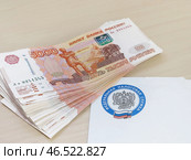 Пачка денег лежит на письме от налоговой службы (2024 год). Редакционное фото, фотограф Татьяна Т / Фотобанк Лори