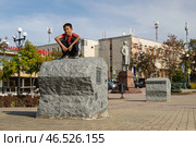 Город Корсаков, Сахалинская область, Россия. Мальчик сидит на корточках на большой каменной глыбе на площади Ленина в центре города Корсакова. На камнях установлены таблички с памятными датами из истории Корсакова. Вдали памятник Владимиру Ленину. Остров Сахалин, Дальний Восток России. Редакционное фото, фотограф Андрей Степанов / Фотобанк Лори